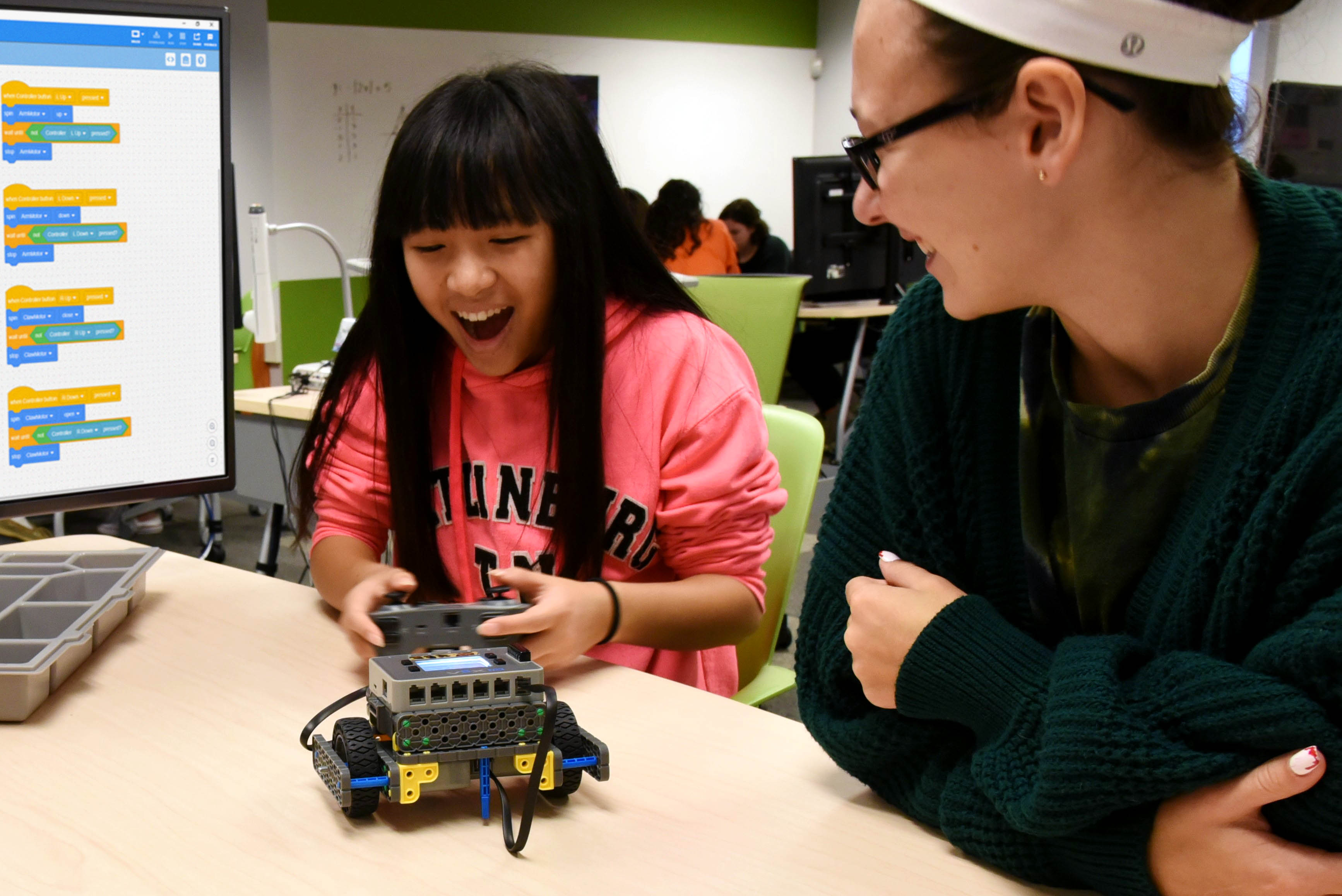 Student working on a vex IQ robot is assisted by their teacher